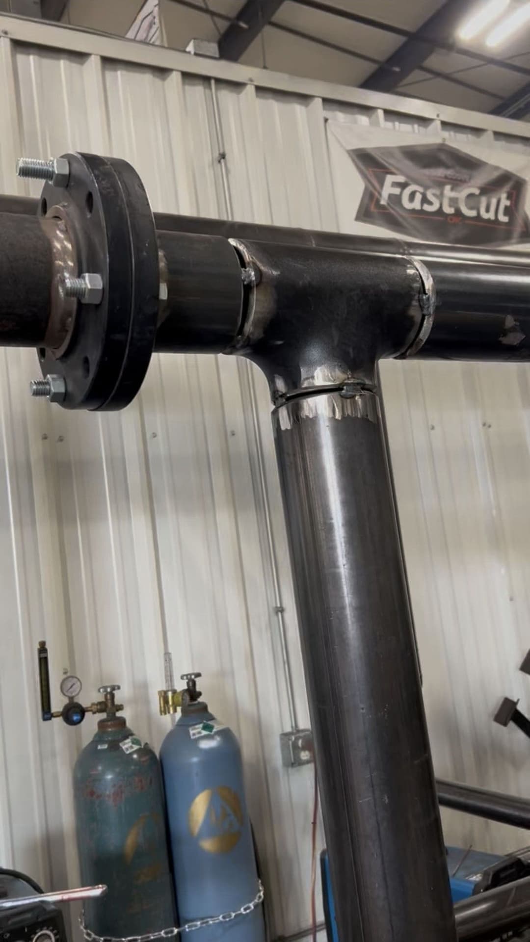 Industrial steel pipe fitting with flanges in a workshop setting, showcasing detailed construction.